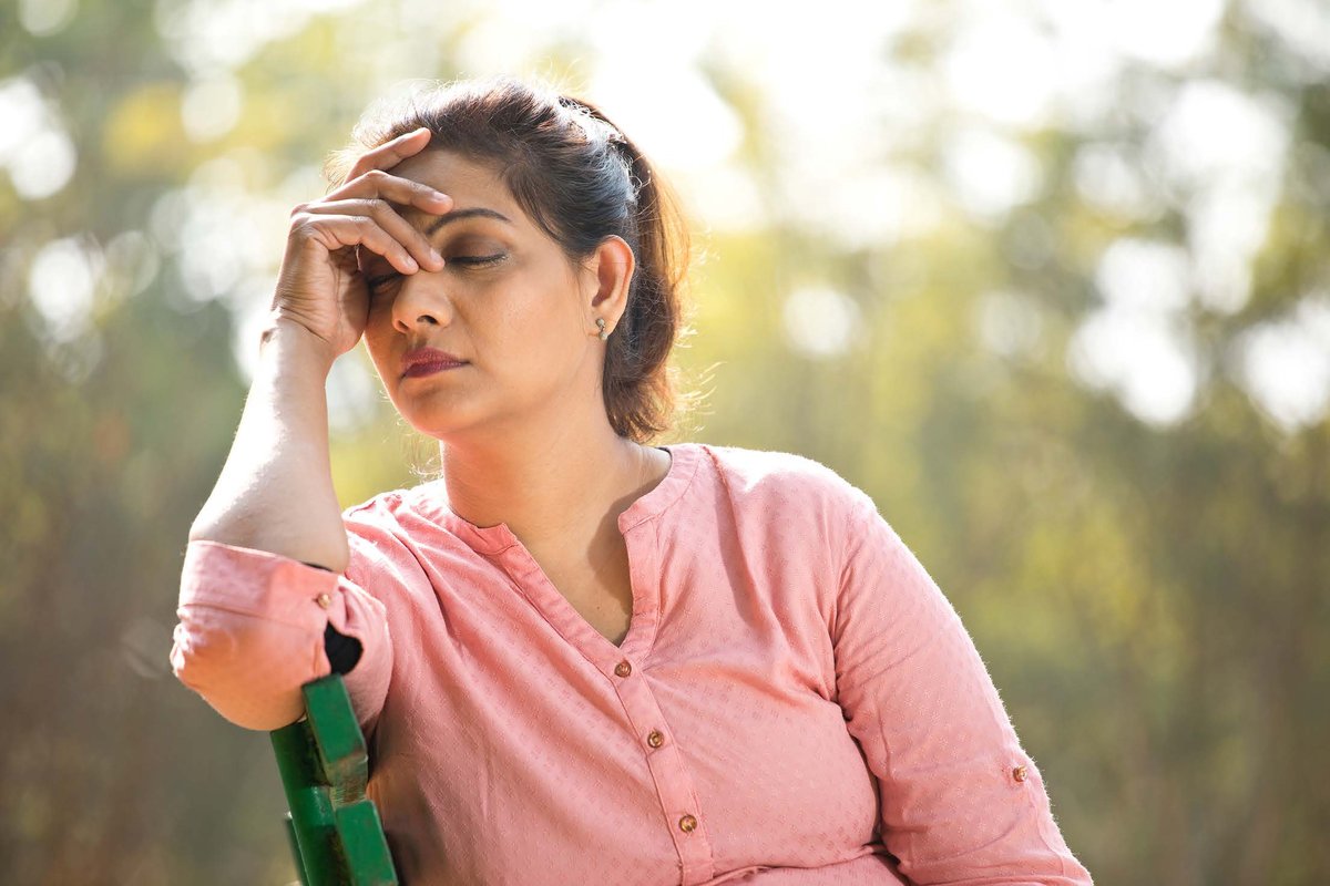 Woman sitting on a bench with her head in her hand, overwhelmed - representing unresolved pain and the need to surrender