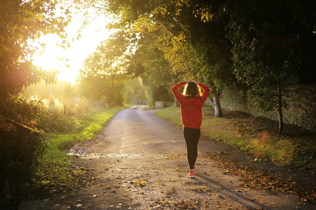 Woman walking alone on a sunlit autumn path - representing a spiritual way of life and inner strength